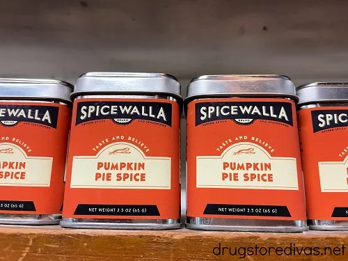 Three tins of Spicewall Pumpkin Pie Spice on a wooden shelf.