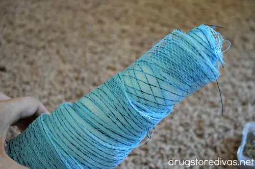 A hand holding a white cone decorated with blue decorative mesh.