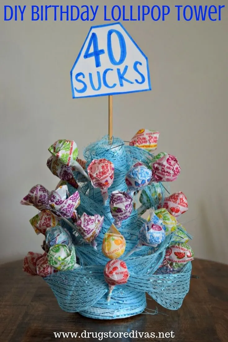 Lollipops and ribbon to form a tower and a 40 sucks tag hanging out the top with the words "DIY Birthday Lollipop Tower" digitally written on top.