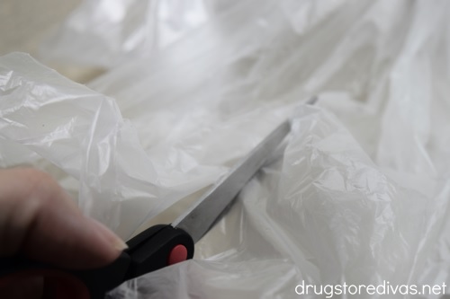 Scissors cutting a white garbage bag.