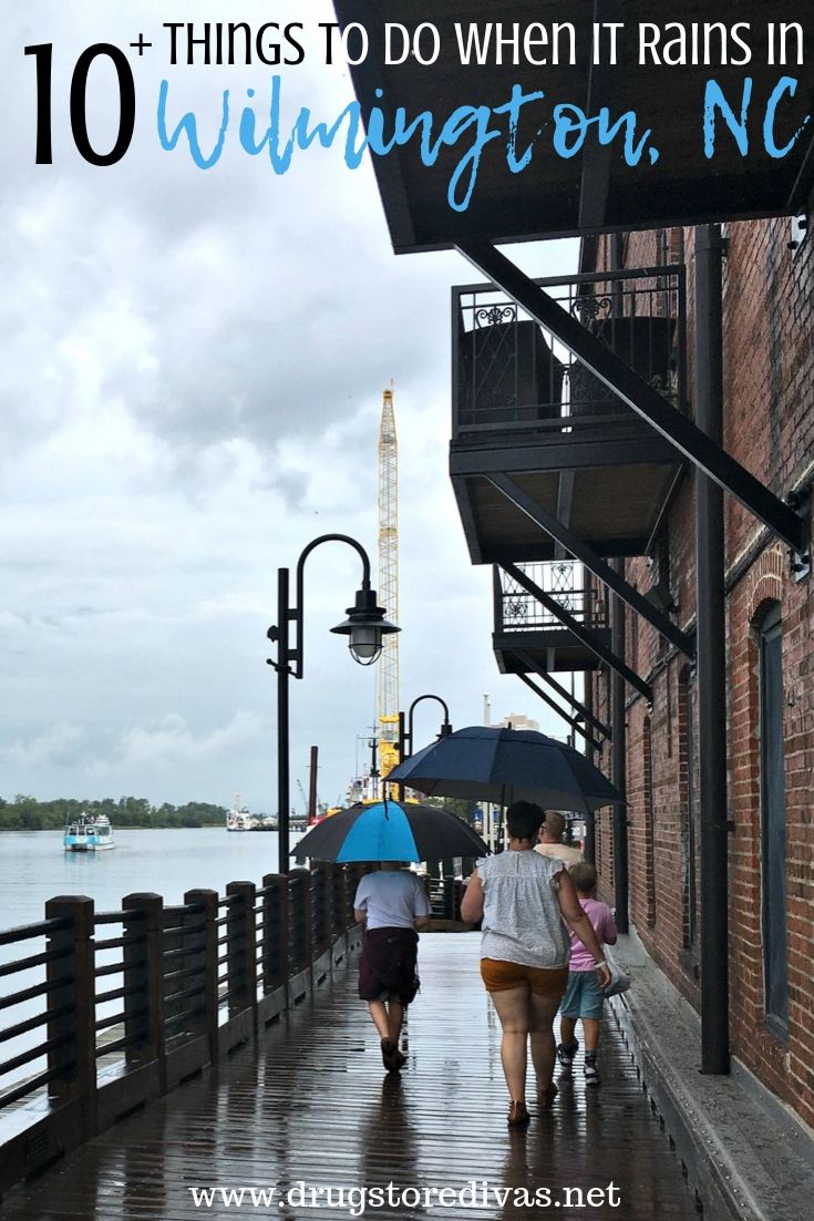 Four people, carrying umbrellas, walking on the riverwalk in Wilmington, NC with the words 