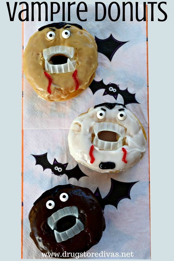 Three donuts decorated to look like vampires with fake teeth and eyes on a white napkin with bats on it.