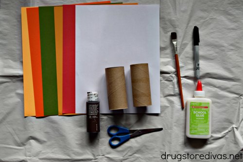 Supplies to make toilet paper roll turkeys, including card stock, toilet paper rolls, paint, scissors, a paint brush, black marker, and glue.