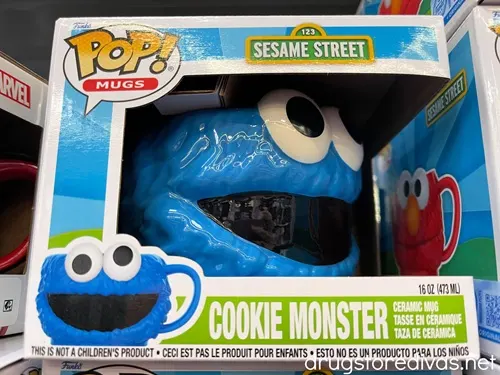 A mug, shaped like Cookie Monster from Sesame Street's face, in a box on a shelf in a store.