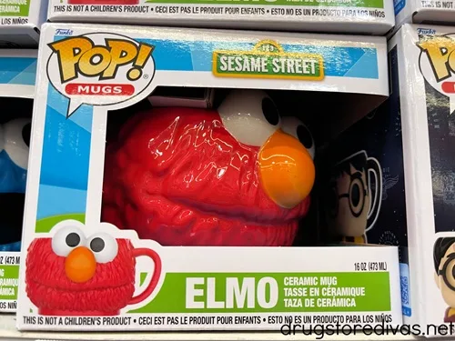 A mug, shaped like Elmo from Sesame Street's face, in a box on a shelf in a store.