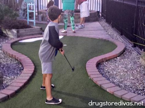 Young boy playing miniature golf.