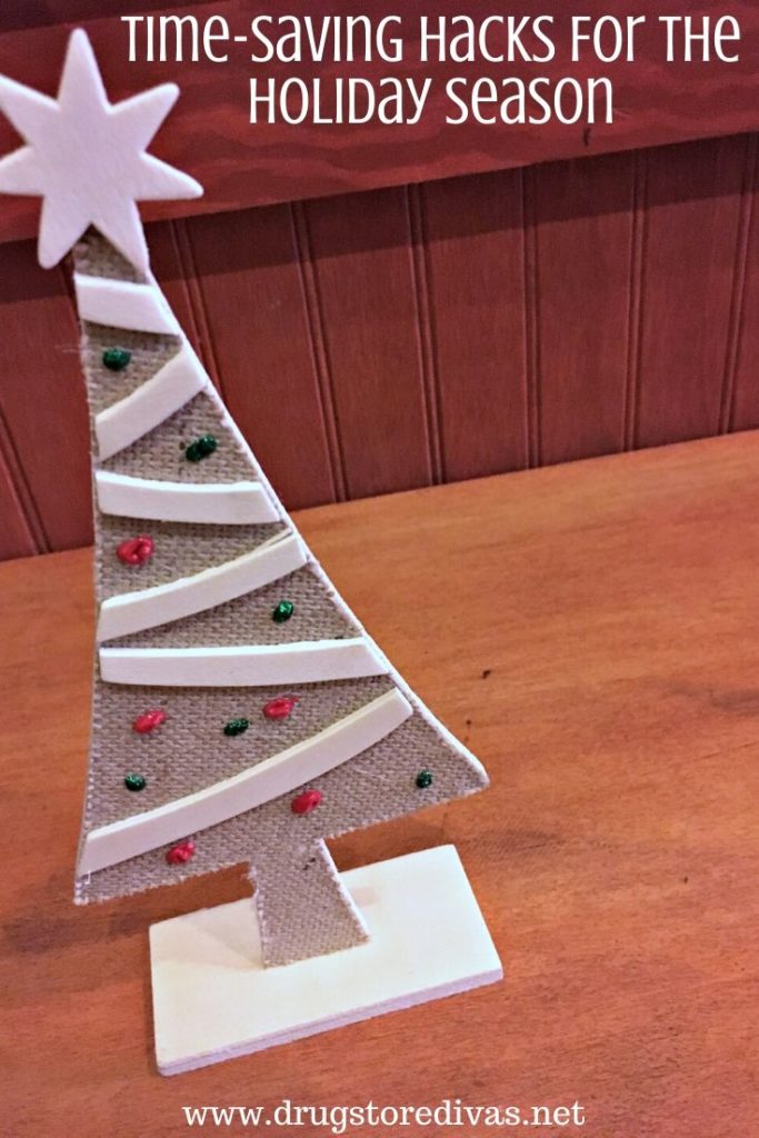 A small wooden Christmas tree with the words "Time-Saving Hacks For The Holiday Season" digitally written above it.