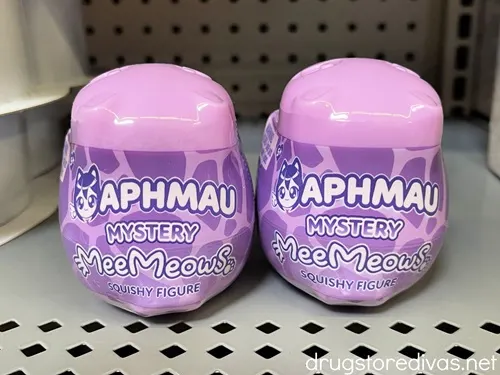 Two purple containers that say Aphmau on them on a shelf.