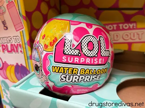 A colorful ball that says LOL Surprise on it in a display on a shelf.
