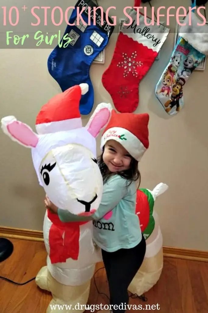 A young girl hugging a blow up llama with the words "!0 Stocking Stuffers For Girls" digitally written above her.