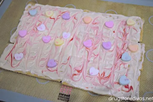 Conversation hearts in red and white chocolate on top of a silicone baking mat.