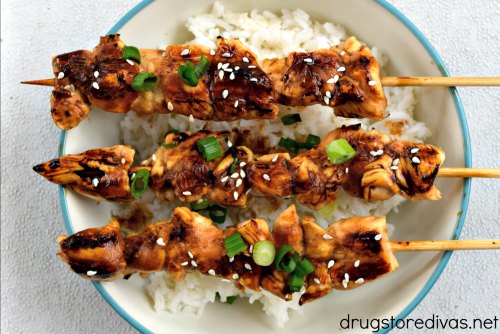 Yakitori (Japanese grilled chicken skewers) over a plate of rice.