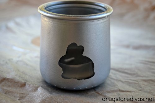A silver jar with a bunny cut out on the front and a tea light inside.