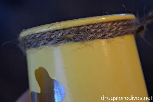 A yellow jar wrapped with jute cording at the top.
