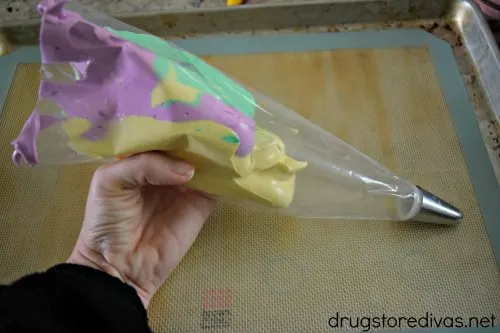 Purple, green, and yellow meringue in a piping bag.