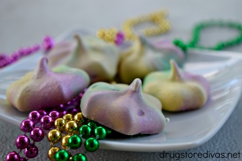 Mardi Gras Meringues cookies on a plate with Mardi Gras beads.