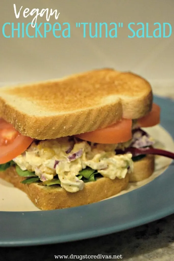 A sandwich with tomato, mashed chickpeas, and lettuce on a plate with the words "Vegan Chickpea Tuna Salad" digitally written on top.