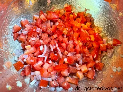 Diced tomato and shallot in a silver bowl.