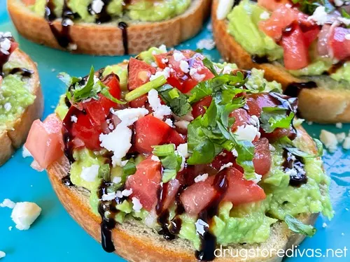 Pieces of avocado toast bruschetta on a blue tray.