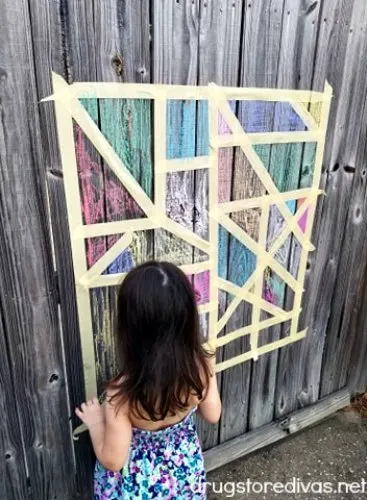 Looking for a fun outdoor kids activity? This Masking Tape And Chalk Mural Craft is perfect. Get details at www.drugstoredivas.net.