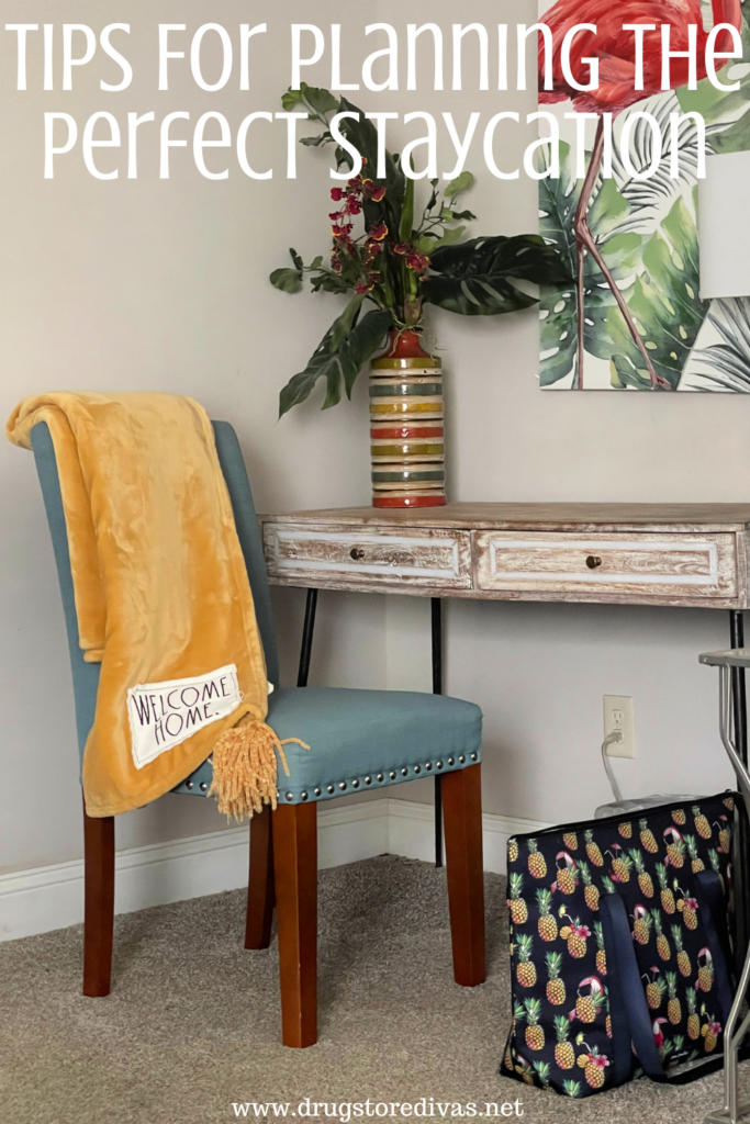 The corner of a home with a desk, the words "Welcome Home" on a blanket on a chair, and a cooler with the words "Tips For Planning The Perfect Staycation" digitally written on top.