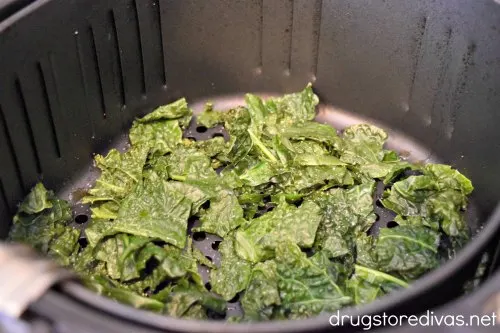 Kale in an air fryer basket.