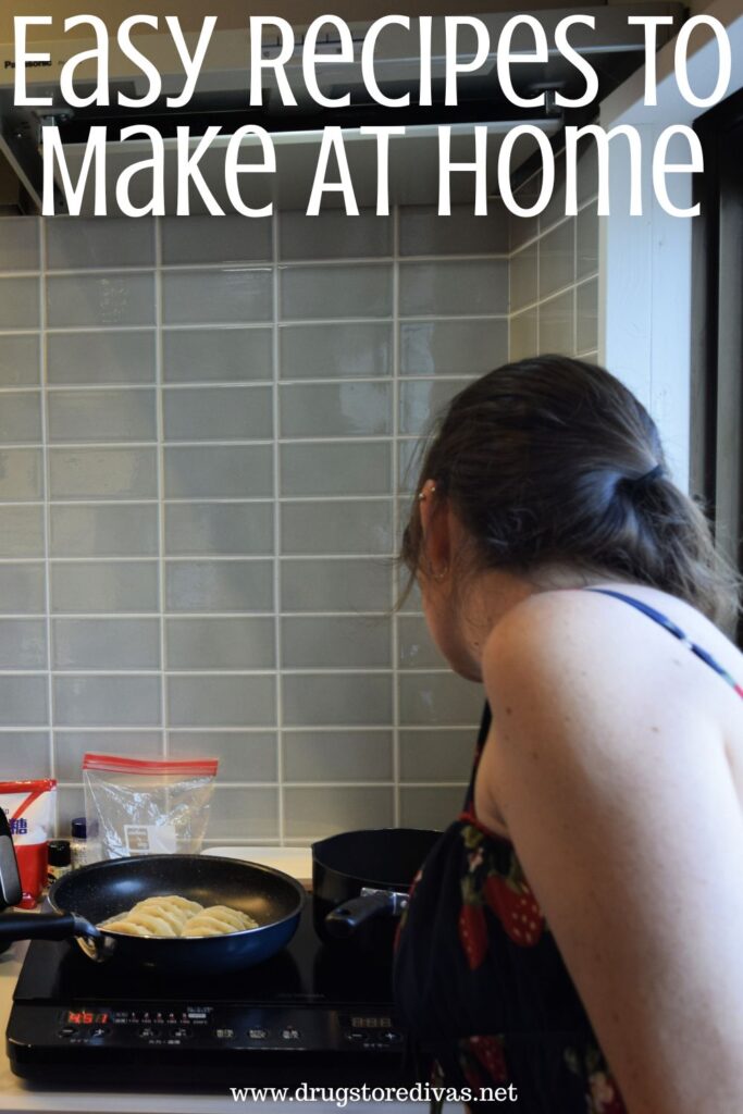 A woman in a dress looking over a stove where a pan of gyoza is cooking with the words "Easy Recipes To Make At Home" digitally written above her.