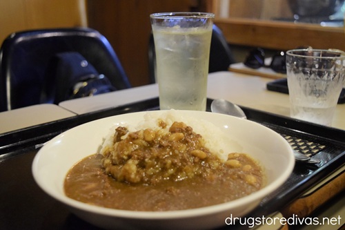 A bowl of Japanese curry and rice on a table with glasses of water behind it.