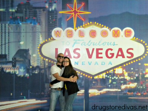 Two people hugging in front of a Welcome to Fabulous Las Vegas Nevada replica sign.