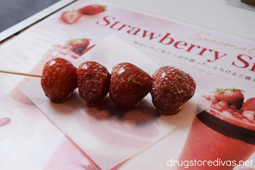 Four candied strawberries, known as tanghulu, on a skewer.