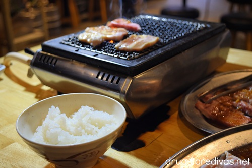 A yakitori grill with meat on it with a bowl of rice in front at a yakiniku restaurant in Japan.
