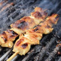 Two chicken kabobs on a grill with the words 
