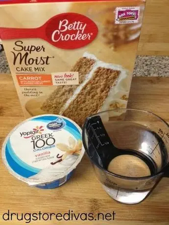 A box of cake mix, a cup of yogurt, and water in a measuring cup.