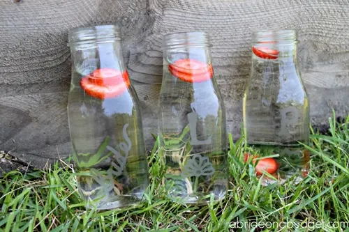 Three glass bottles of water with strawberry slices in them.