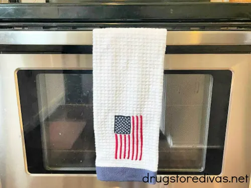 An American Flag kitchen towel hanging on an oven.