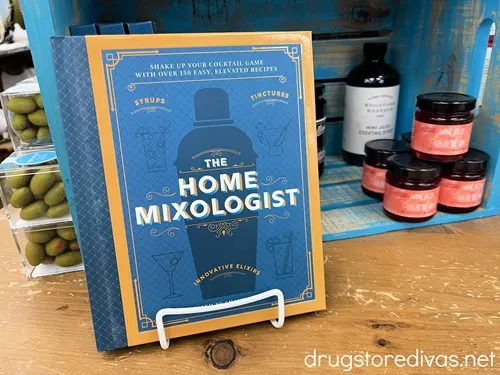 Have a cocktail lover on your shopping list? Need a gift for a home mixologist? This list from www.drugstoredivas.net has you covered. The Home Mixologist book on a shelf with some bottles behind it.
