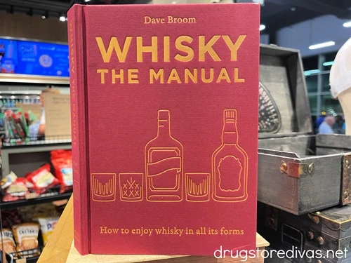 A red book called Whisky The Manual on a shelf.