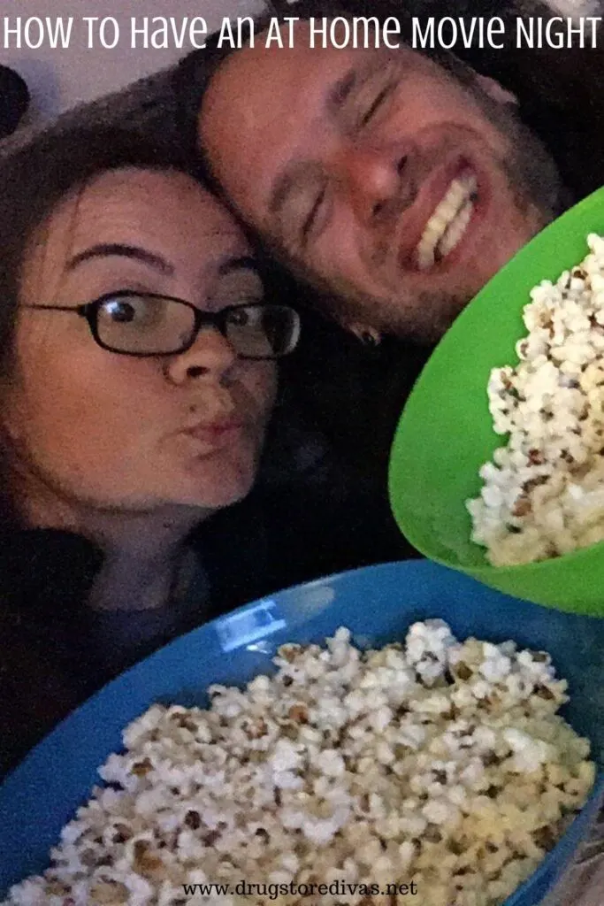 A man and a woman, holding popcorn, with the words "How To Have An At Home Movie Night" digitally written on top.