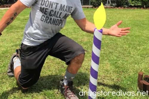 Man kneeling near a pool noodle made to look like a birthday candle.
