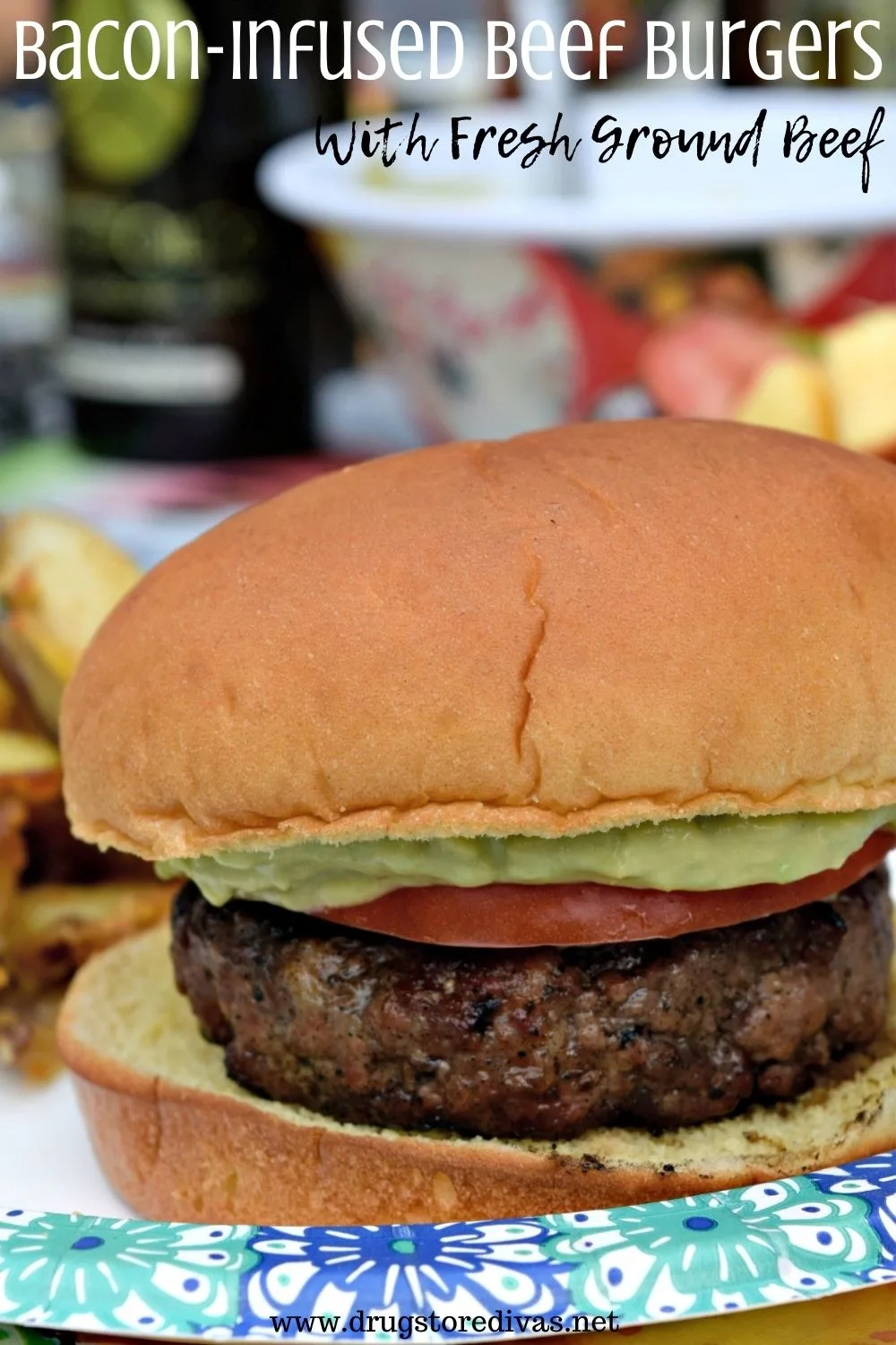 A Burger with avocado mash and a tomato slice on a paper plate.