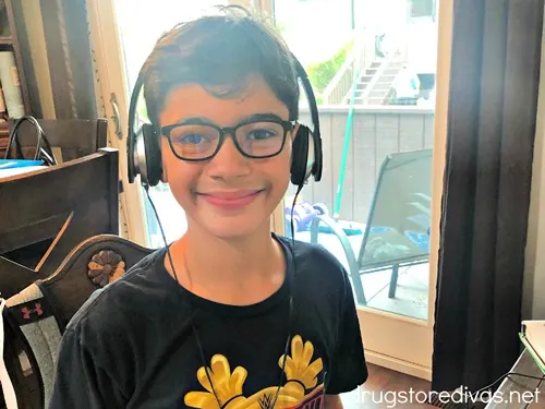 A young boy in a black shirt wearing bluelight blocking glasses and headphones.