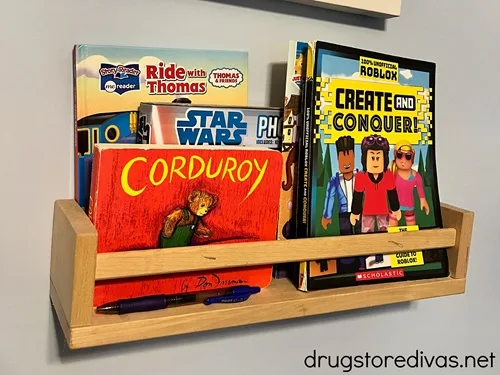 A floating book shelf on a wall with kids books in it.
