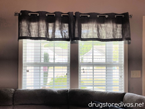 A window in a living room with blinds and a valance on top.
