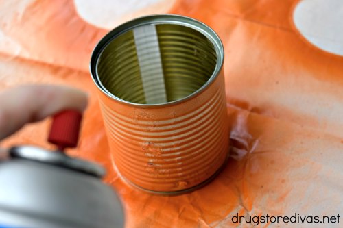 A can of spray paint spraying a tin can.