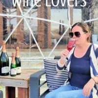 A woman sipping a drink next to three wine bottles with the words 