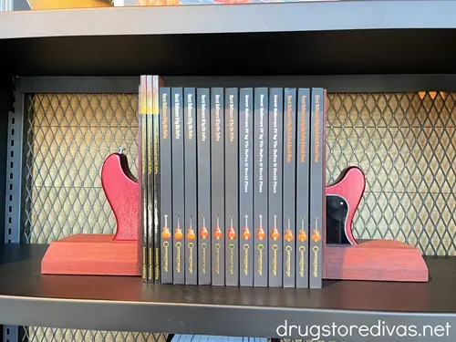 Guitar-shaped book ends with books between them on a shelf.