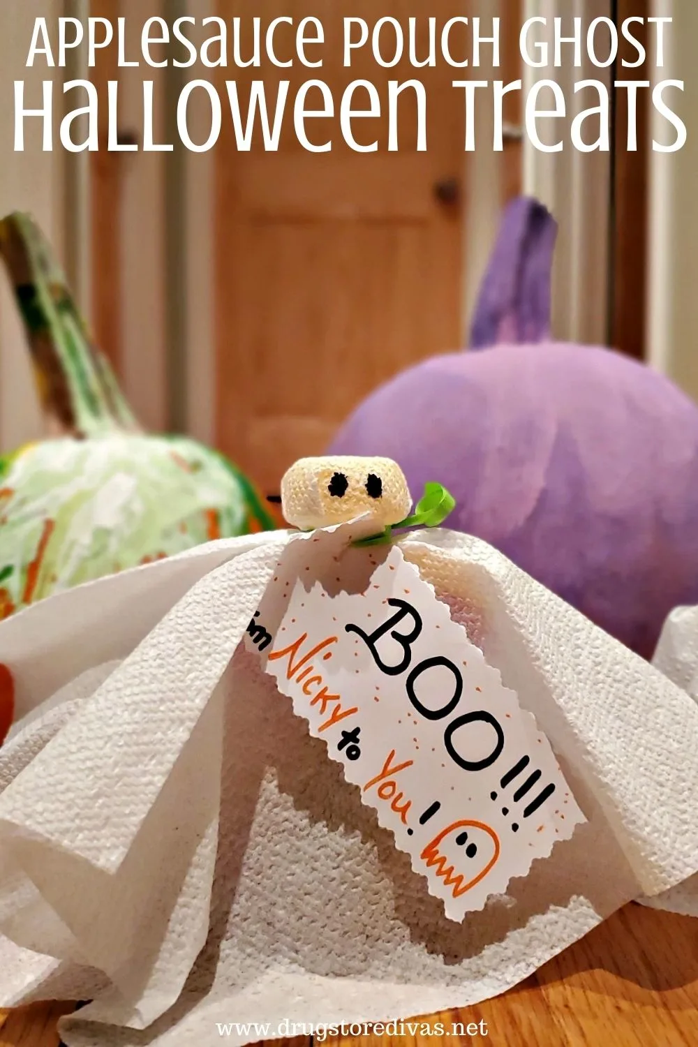 These Applesauce Pouch Ghost Halloween Treats are adorable. Plus, they're an allergy-free Halloween treat. Find out how to make them on www.drugstoredivas.net. A napkin ghost in front of a green and a purple pumpkin with the words "Applesauce Pouch Ghost Halloween Treats" digitally written on top.