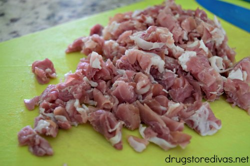 Sliced prosciutto, chopped into pieces, on a neon green cutting board.