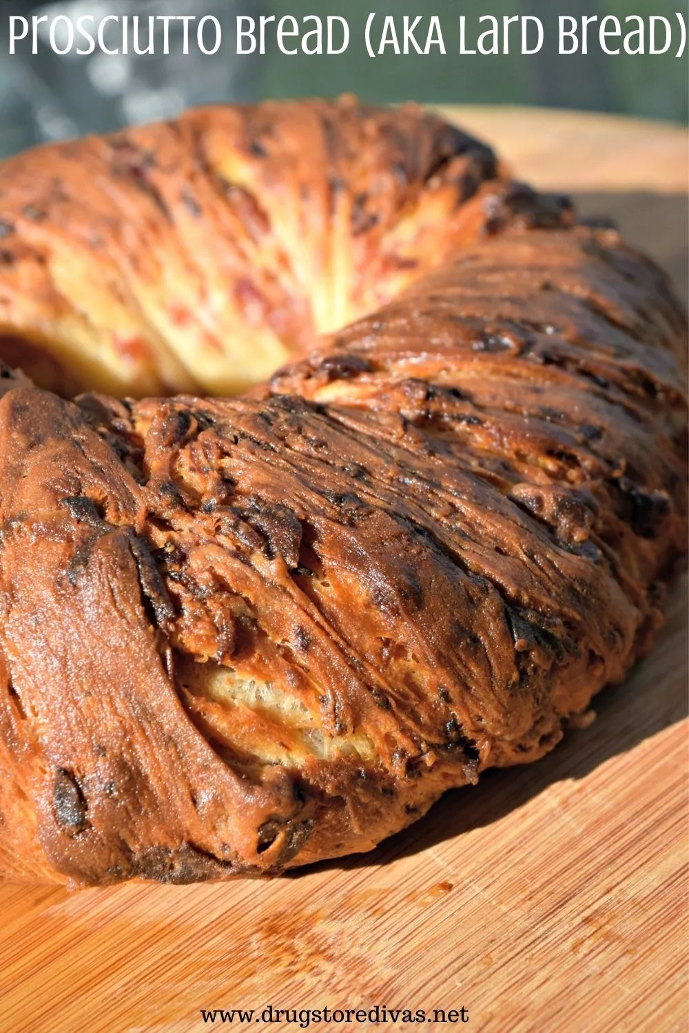 Ring of prosciutto bread on a wooden cutting board.