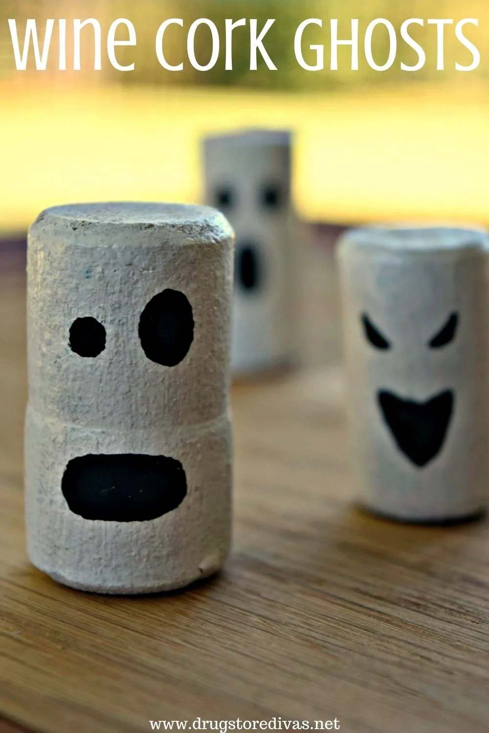Three wine corks painted to look like ghosts with the words "Wine Cork Ghosts" digitally written on top.
